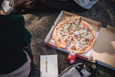 faceless men sitting on ground with pizza